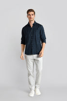 Man wearing a dark blue shirt and light gray pants on a gray background