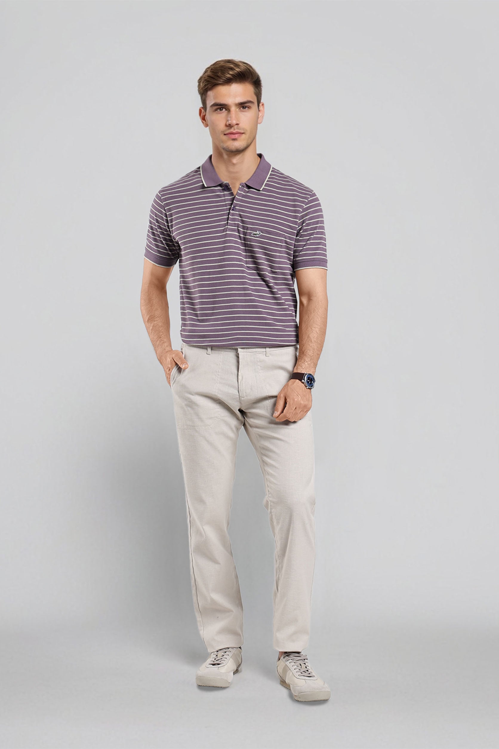 Man wearing a striped polo shirt and beige pants on a gray background