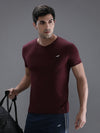 Man wearing a red wine red solid casual t shirt with casual styling on a gray background