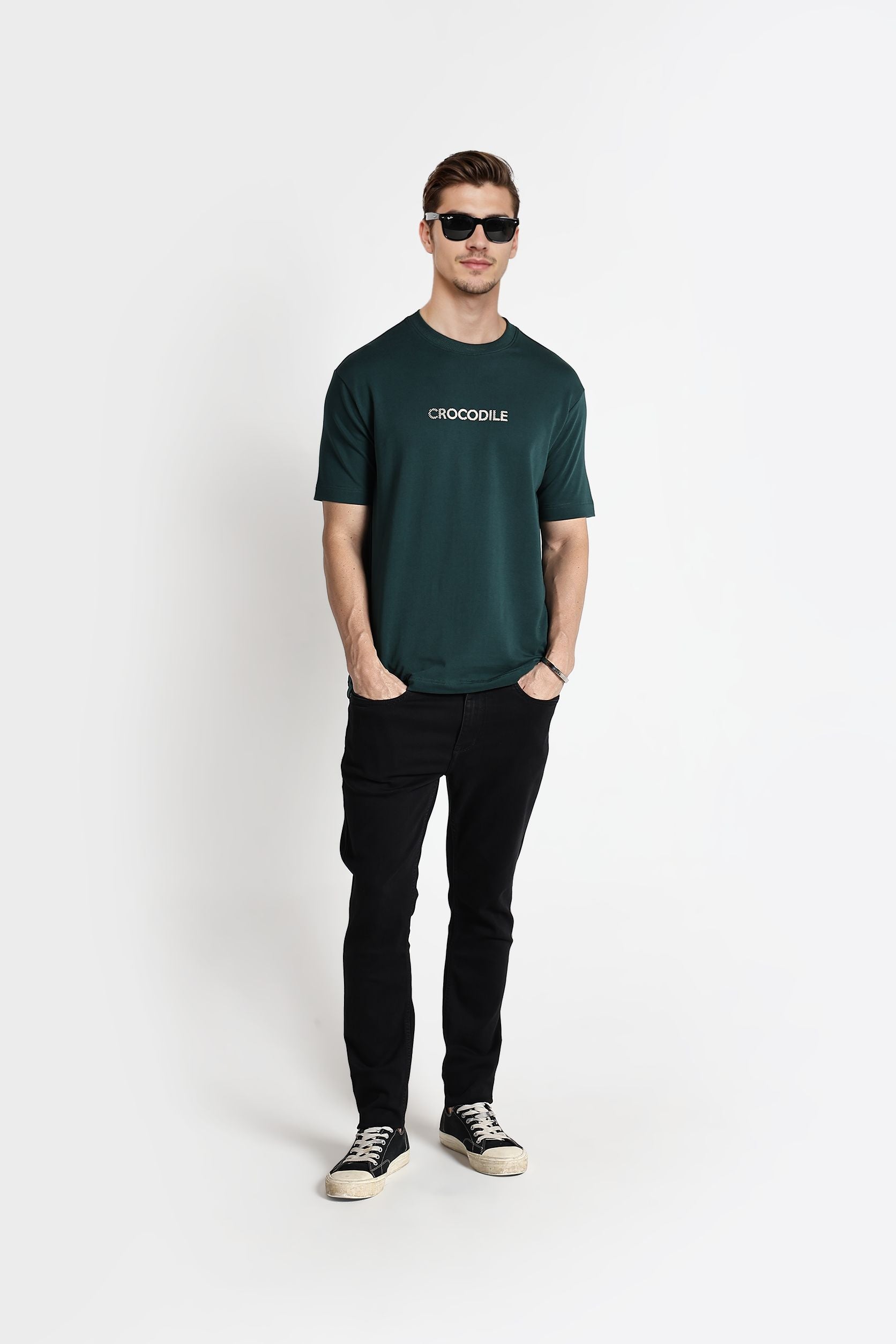 Man wearing a green t-shirt with 'Crocodile' logo and black pants on a white background