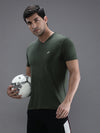 Man wearing a green solid green sport fit t shirt with casual styling on a gray background