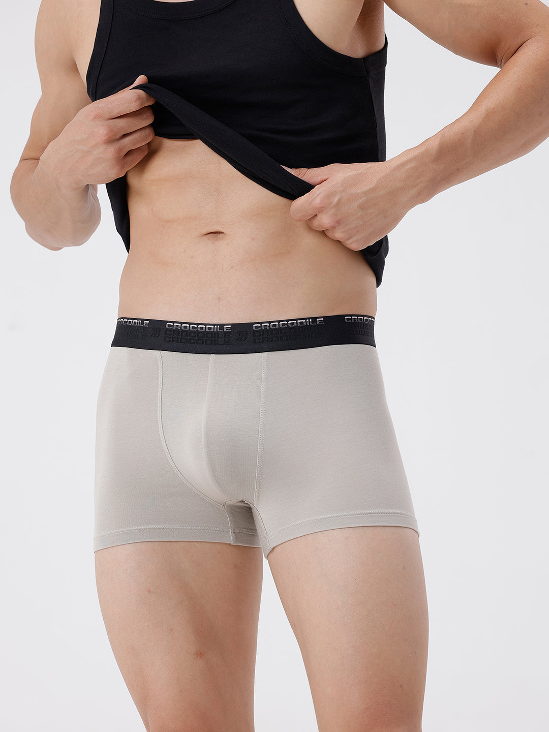 Person wearing beige boxer briefs with a black waistband on a white background