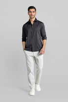 Man wearing a black shirt and white pants on a gray background