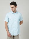 Man wearing a blue blue solid half sleeve shirt with casual styling on a gray background
