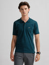 Man wearing a green solid slim fit green polo t shirt with casual styling on a gray background
