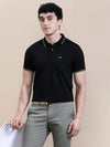 Man wearing a black casual polo t shirt solid black with pocket on a light gray background
