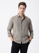 Man wearing a beige linen blend shirt in dark beige on a light gray background