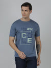 Man wearing a blue typography printed single jersey blue cotton t shirt with casual styling on a gray background