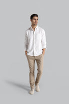 Man wearing a white shirt and beige pants on a gray background