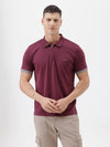 A man wearing a short-sleeve polo shirt in maroon with gray sleeve trim and a half-zip collar, paired with beige cargo pants, against a plain white studio background.