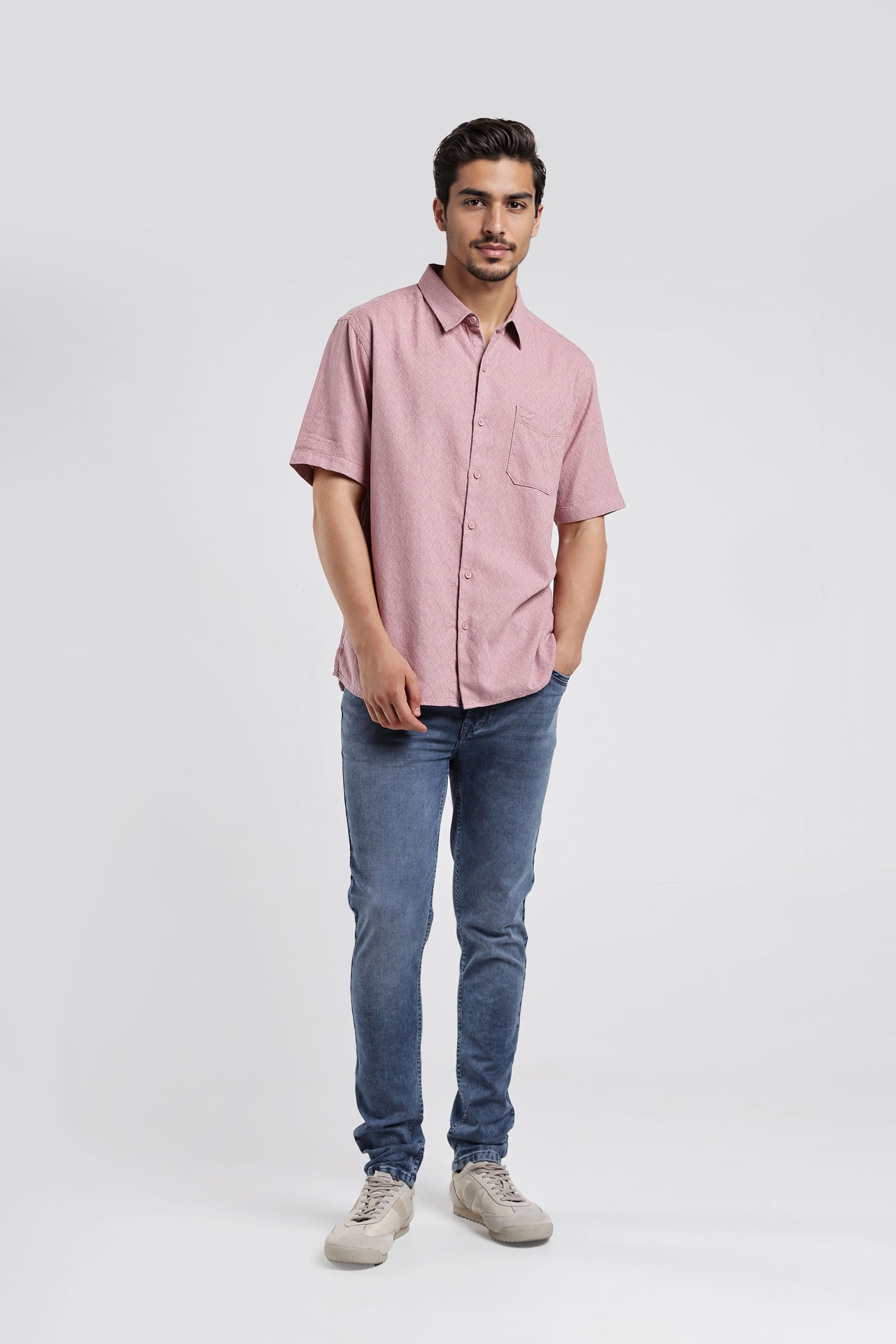 Man wearing a pink shirt and blue jeans on a white background