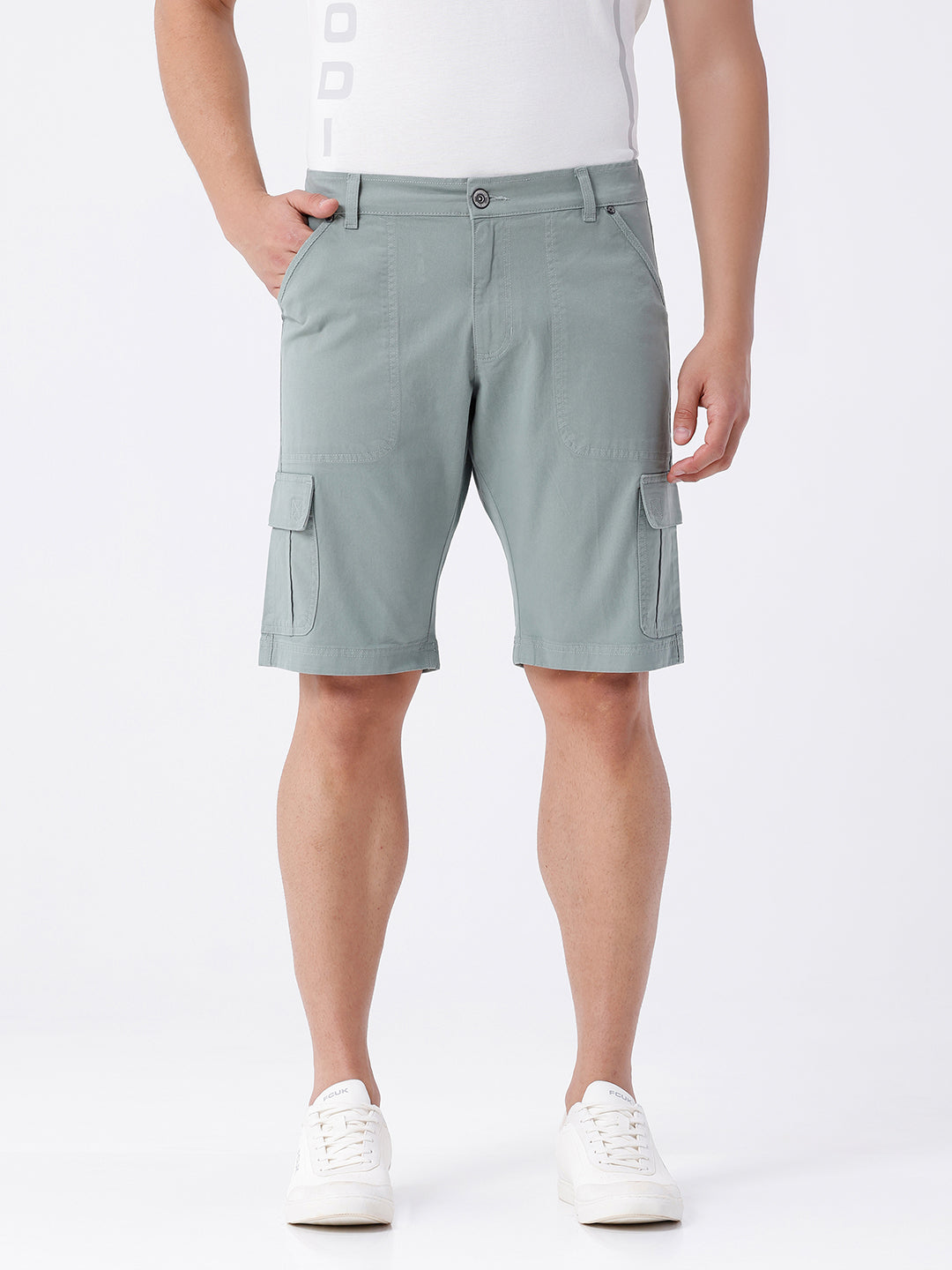 Man wearing a olive garment dyed cargo shorts in olive on a light gray background
