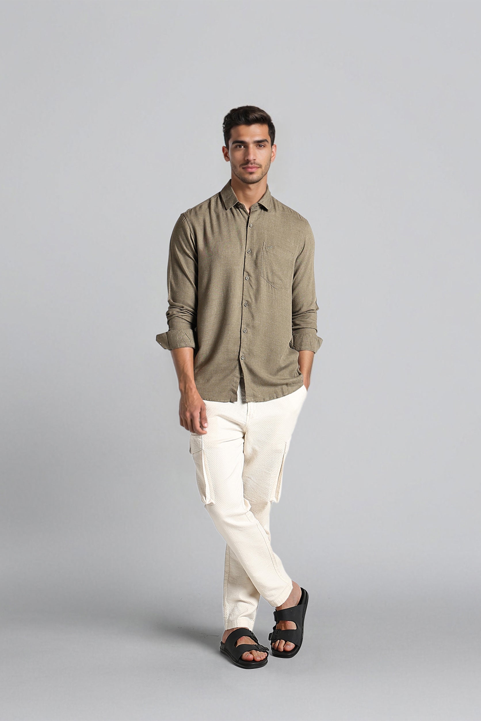 Man wearing a green shirt and white pants on a gray background