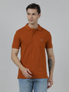 Man wearing a brown solid brown slim fit polo t shirt with pocket on a light gray background