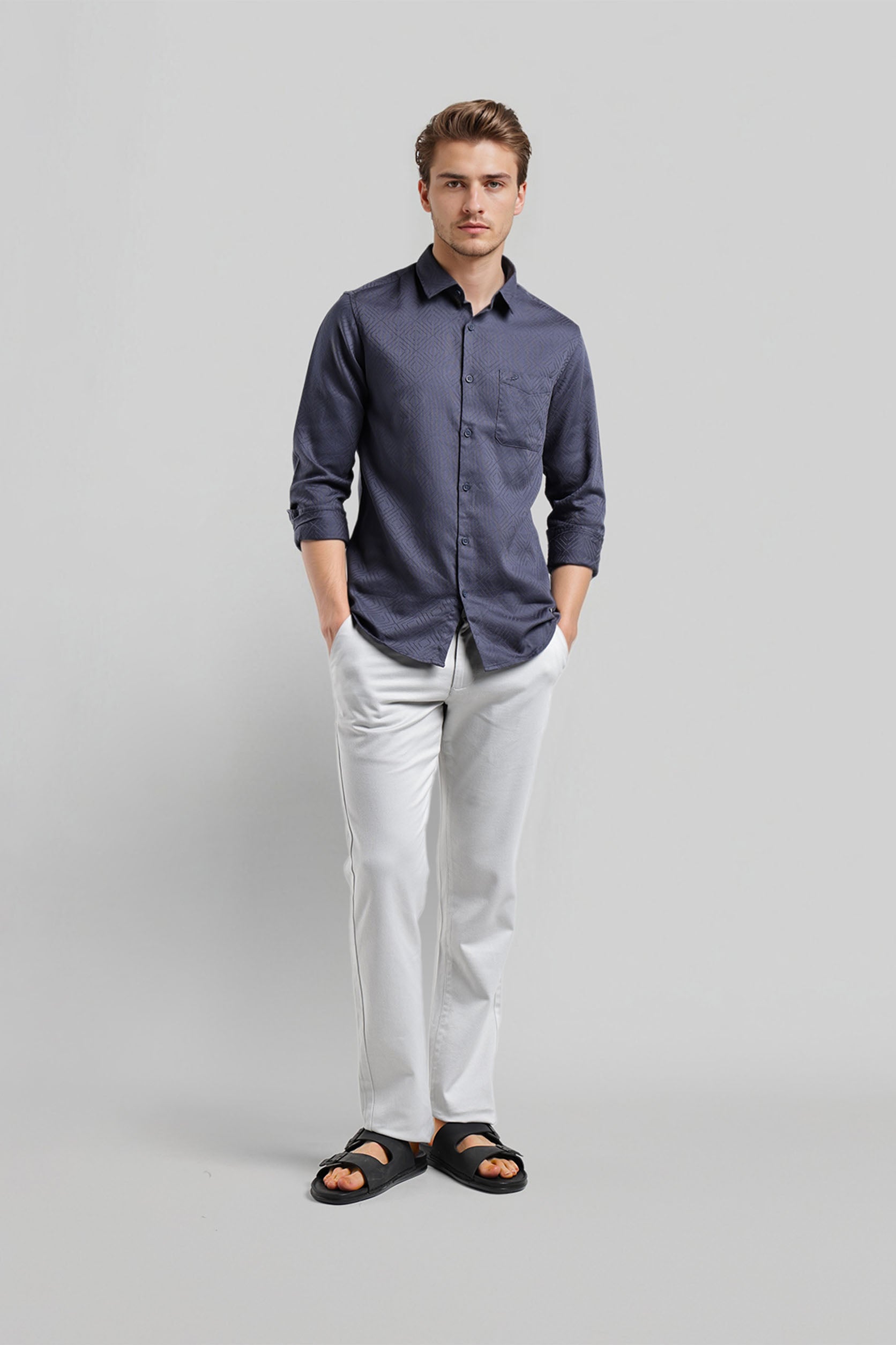 Man wearing a blue shirt and white pants on a gray background