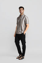 Man wearing a striped shirt and black pants on a light gray background