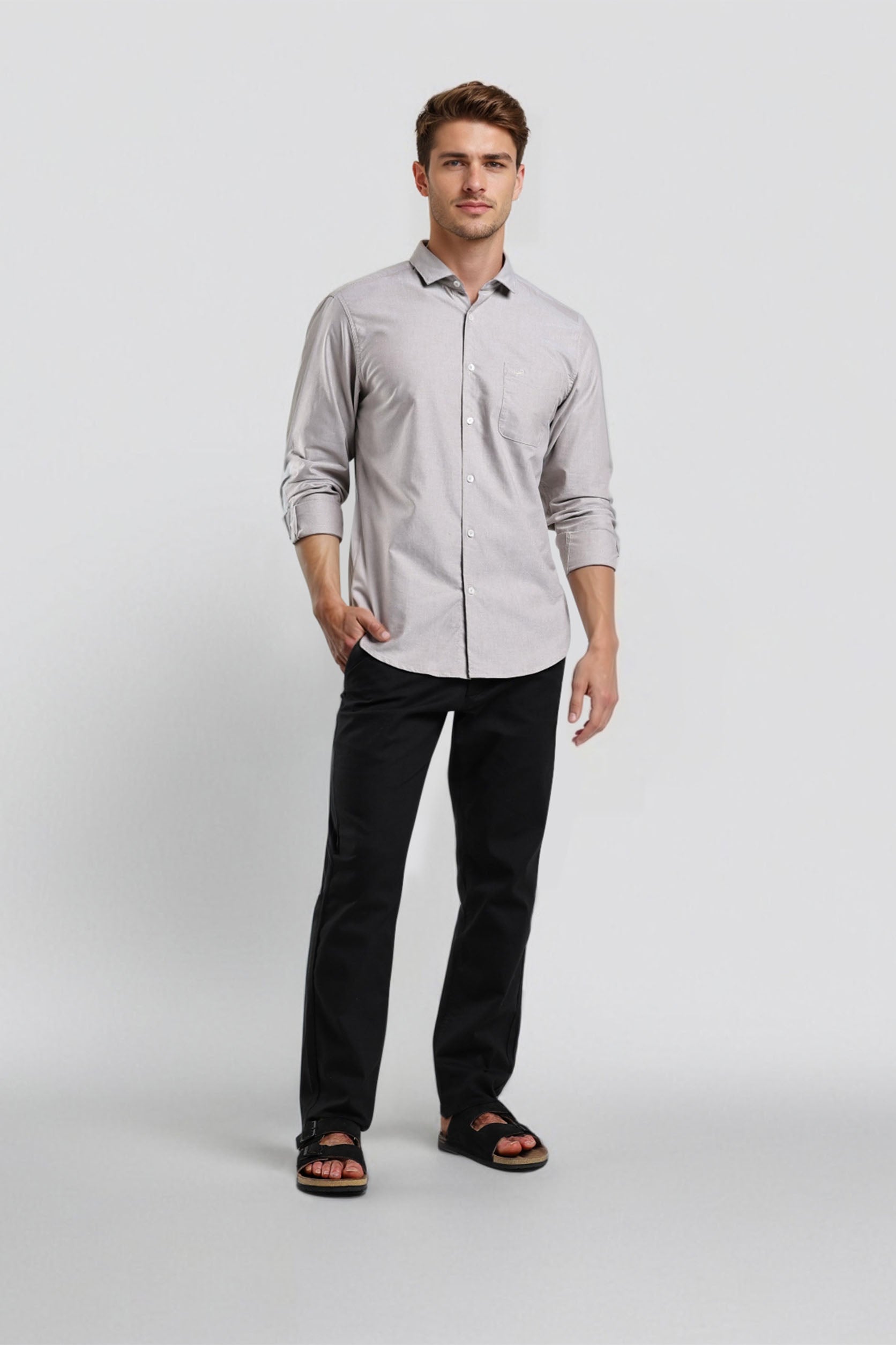 Man wearing a light gray button-up shirt and black pants on a white background