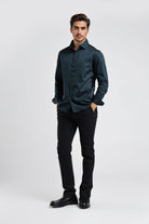 Man wearing a dark green shirt and black pants on a white background