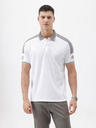 A man modeling a white short-sleeve polo shirt with gray shoulder panels and gray striped trim on the sleeves, paired with gray trousers and black sunglasses, against a plain white background.