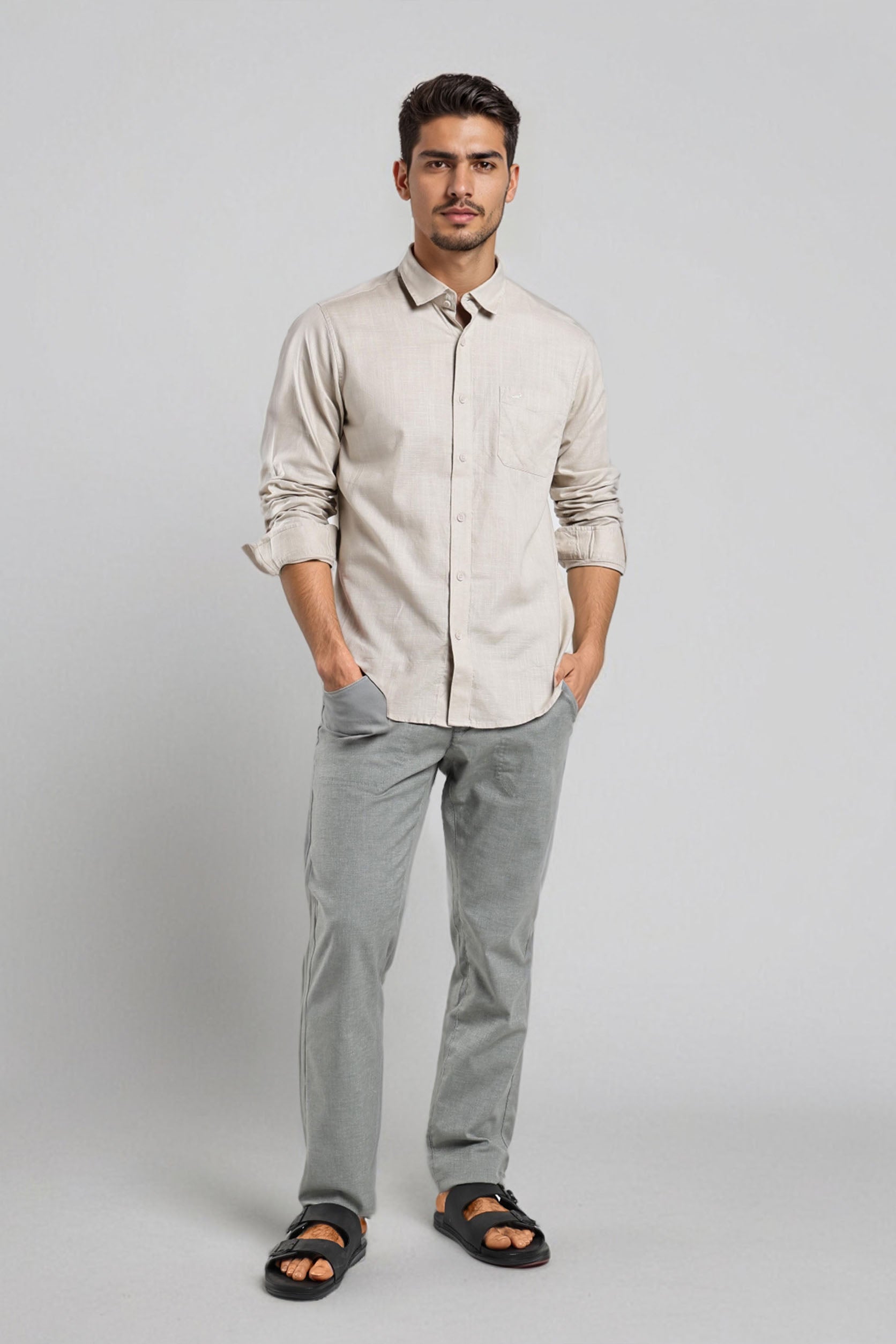 Man wearing a beige shirt and gray pants on a white background
