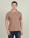 Man wearing a brown light brown solid polo t shirt on a light gray background