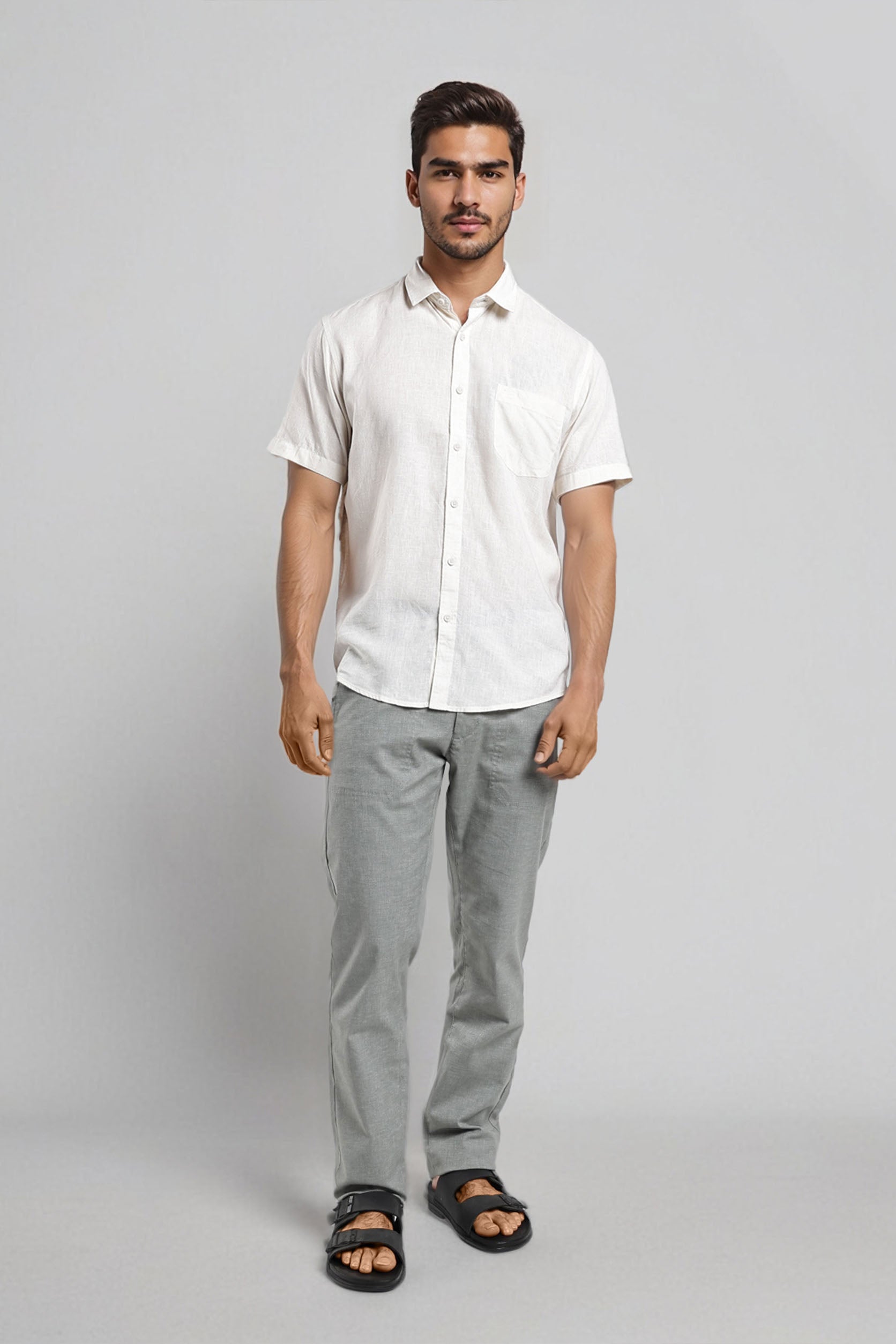 Man wearing a white shirt and gray pants on a plain background