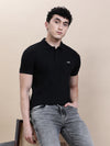 Man wearing a black casual solid black polo t shirt with pocket with casual styling on a gray background