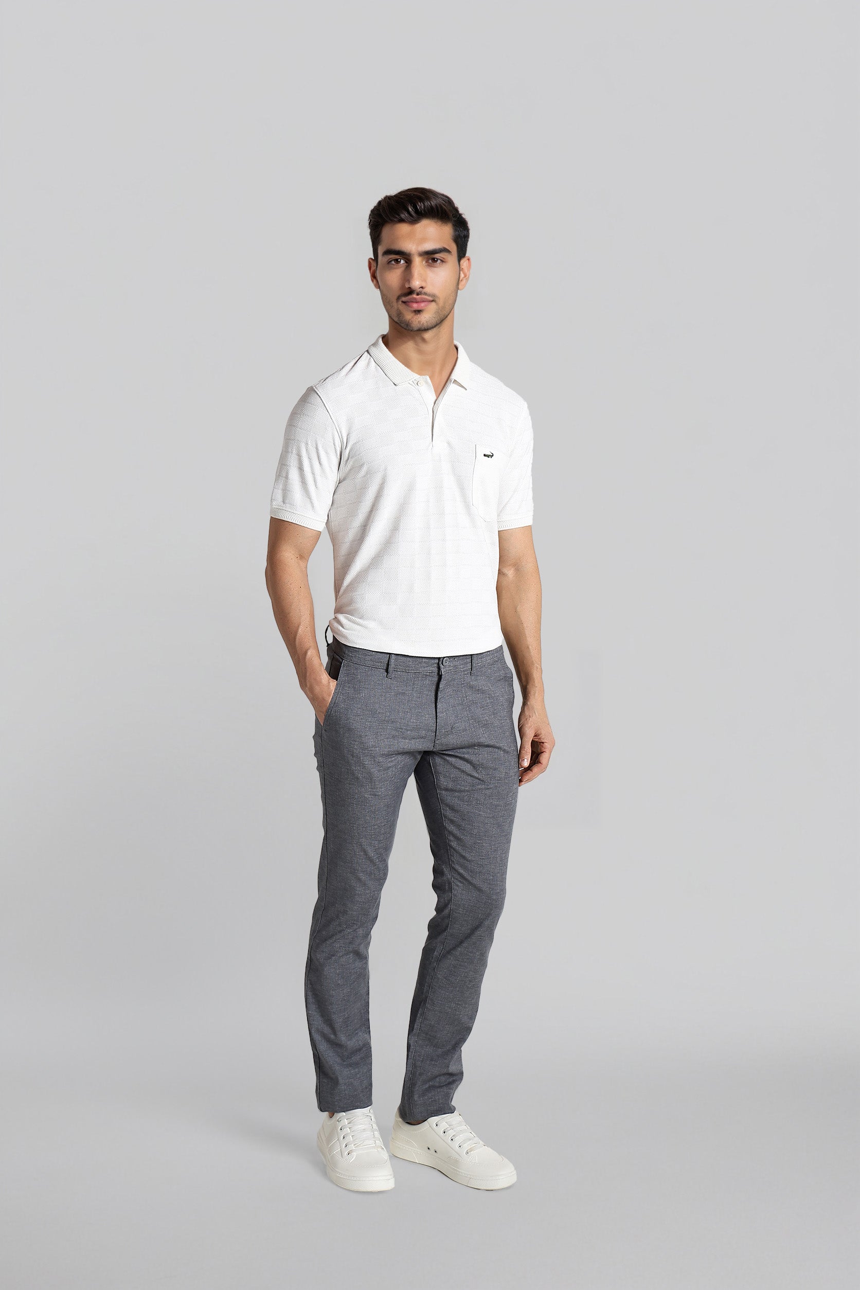 Man wearing a white polo shirt and gray pants on a light gray background