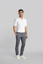 Man wearing a white polo shirt and gray pants on a light gray background