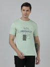 Man wearing a green typography printed single jersey cotton green t shirt with casual styling on a gray background