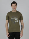 Man wearing a green typography printed single jersey cotton olive green t shirt on a light gray background