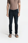 Man wearing a green green premium tinted soft fabric slim fit jeans on a light gray background