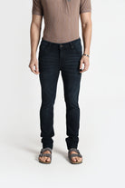 Person wearing dark jeans and a brown shirt on a white background