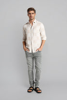 Man wearing a light-colored shirt and gray pants on a gray background