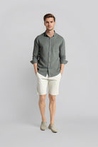 Man wearing a gray shirt and white shorts on a light gray background