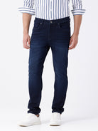 Man wearing a blue dark blue knit slim fit jeans with casual styling on a gray background