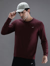 Man wearing a red casual wine red solid t shirt on a light gray background