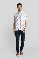 Man wearing a patterned shirt and dark jeans on a gray background