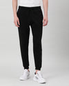 Man wearing a black black comfort fit solid joggers with casual styling on a gray background