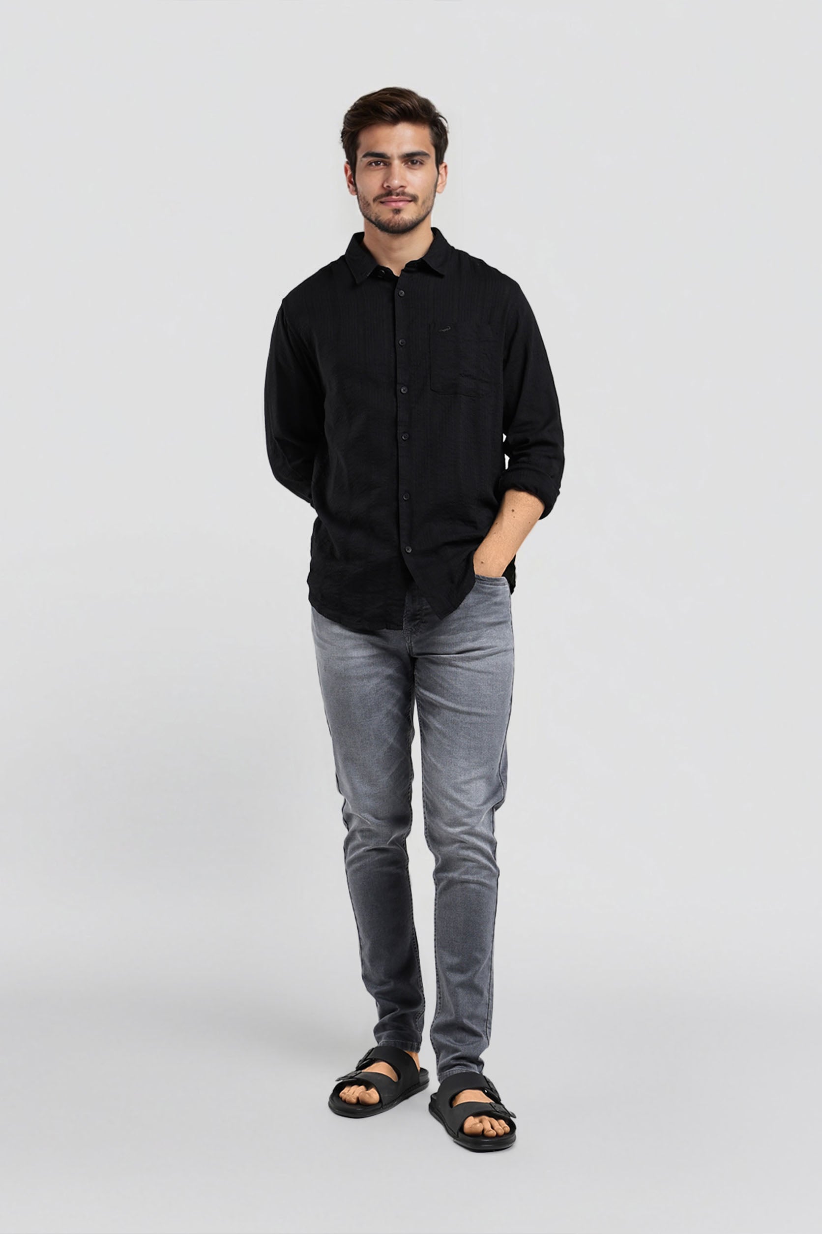Man wearing a black shirt and gray jeans on a white background