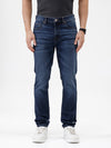 A person wearing dark blue slim-fit jeans with a faded wash, paired with a black t-shirt and white sneakers, shown from the waist down against a plain white studio background.