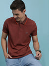 Man wearing a brown casual polo t shirt brown printed on a light gray background