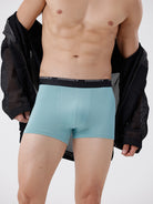 Person wearing light blue boxer briefs with a black jacket on a white background