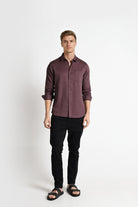 Man wearing a brown button-up shirt and black pants on a white background