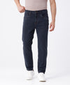 Man wearing a blue blue grey natural fade wash rugged jeans on a light gray background