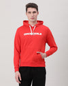 Man wearing a red solid artisanal red hoodie with casual styling on a gray background