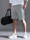 Man wearing a grey solid grey comfort fit track shorts on a light gray background