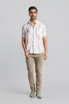 Man wearing a patterned shirt and beige pants on a gray background