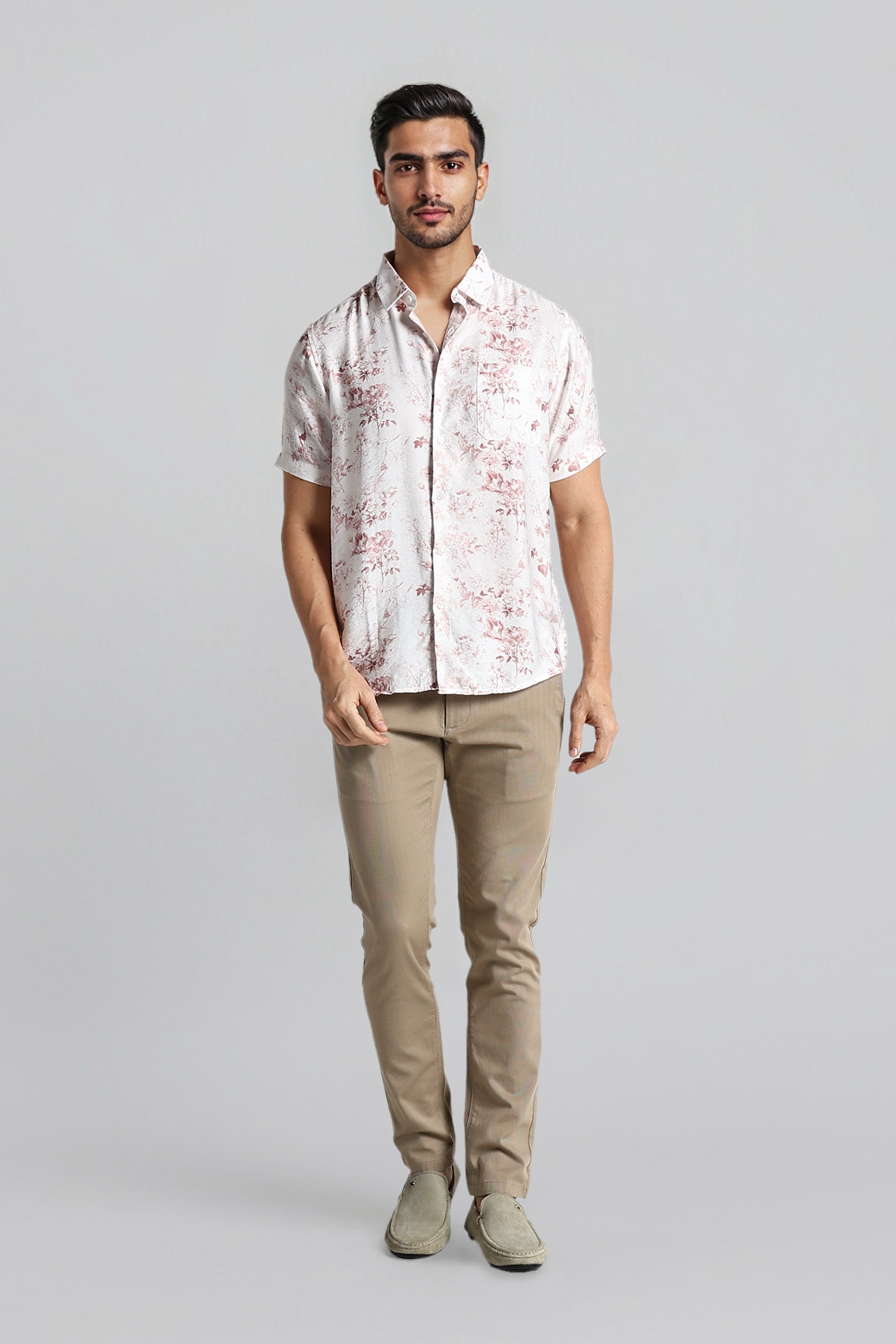 Man wearing a patterned shirt and beige pants on a gray background