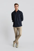 Man wearing a dark shirt and beige pants on a light gray background